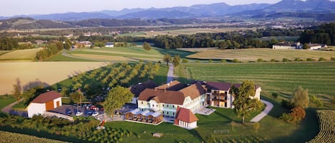 A large estate with multiple buildings, expansive fields, and a mountainous backdrop.