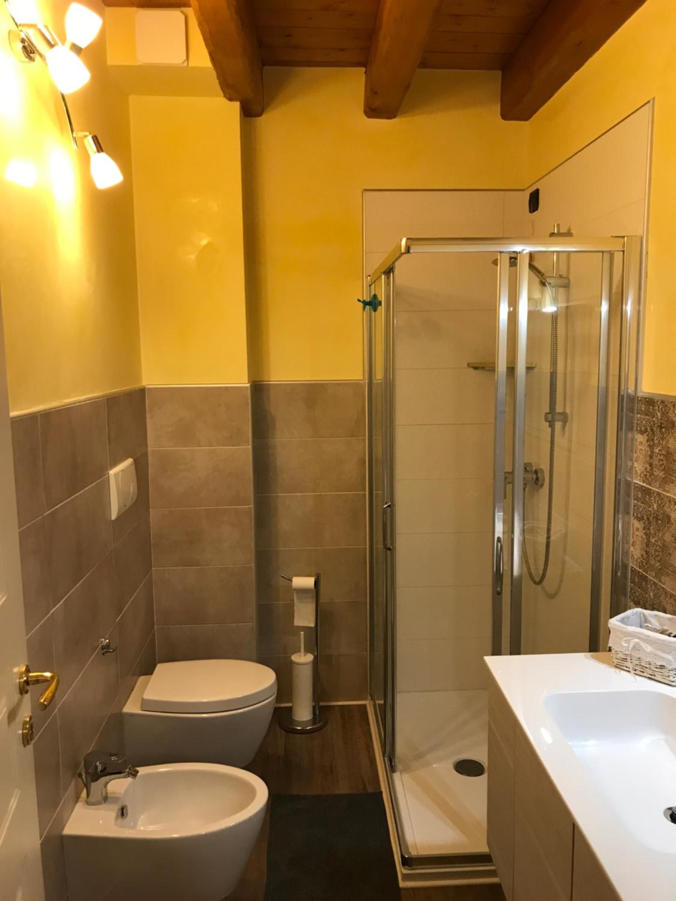 Un bagno con doccia vetro-muraria, un water, un bidet e un lavandino.
