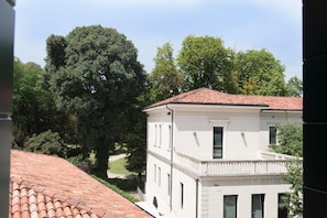 A two-story building with a white facade and a red-tiled roof. - Residence Eremitani (Padova)