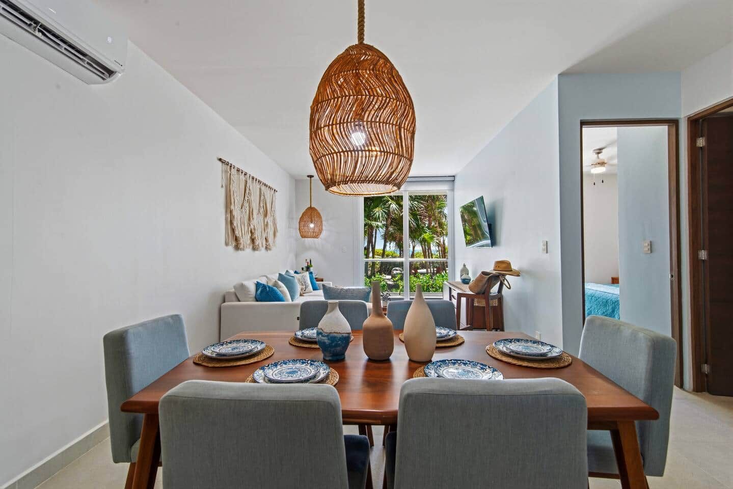 A dining area with a wooden table set for four, surrounded by grey upholstered chairs.