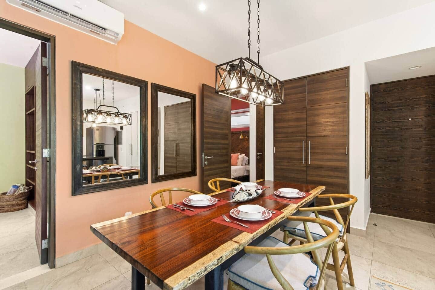 A dining area with a wooden table, chairs, and a hanging light fixture.