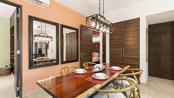 A dining area with a wooden table, chairs, and a hanging light fixture.