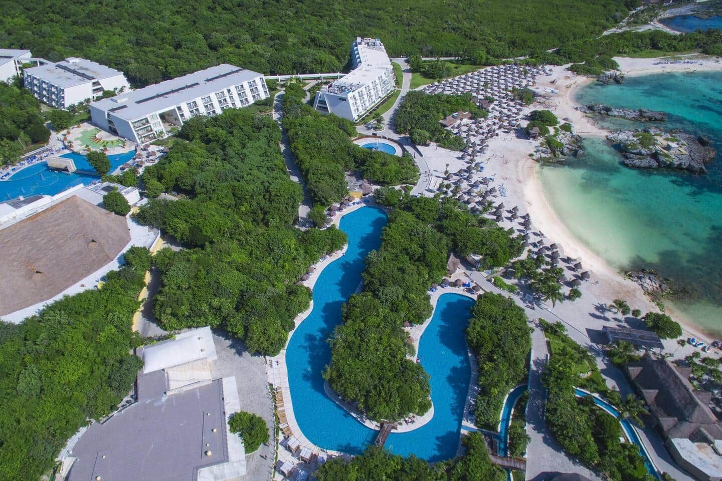 A resort with multiple swimming pools, a beach, and a large building complex.