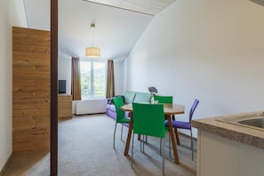 Una cocina moderna con comedor, una ventana con cortinas y vistas a zonas verdes.