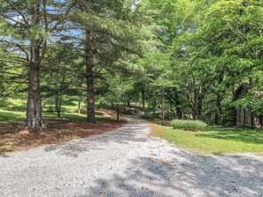 A gravel path flanked by trees and a wooden structure.