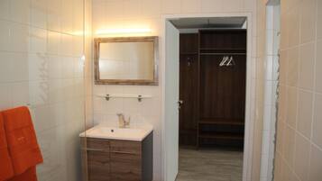 A bathroom with white tiles, a wooden vanity, a mirror, and a towel rack.