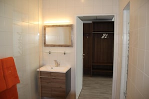 A bathroom with white tiles, a wooden vanity, a mirror, and a towel rack. - Nemetz Motel (Boheimkirchen)