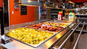 A buffet with various food options including potatoes, sausages, and salads.