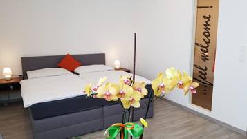 A hotel room with a bed, a nightstand, a lamp, and a decorative orchid arrangement.