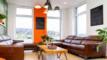 A modern interior with leather sofas, a wooden coffee table, and large windows offering a view of the outdoors.