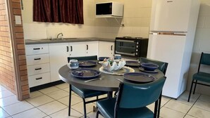 Una cocina con una mesa de comedor, sillas, microondas, refrigerador y lavaplatos.
