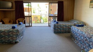 Una habitación con dos camas, un ventilador de techo y vistas al exterior.