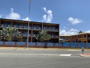 A multi-story motel with a brick facade, balconies, and a fenced parking area.