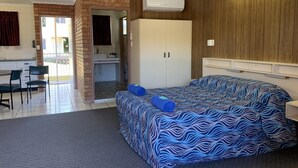 Un dormitorio con cama, armario, escritorio y silla.