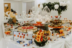 Una mesa de buffet con diferentes tipos de comida y un centro de mesa decorativo con forma de pájaro.