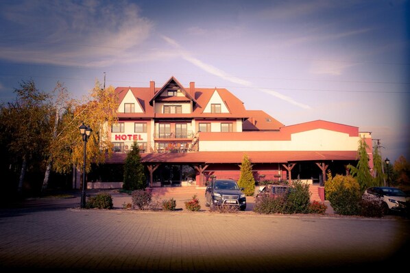 A two-story hotel with a red roof and a sign that reads 'HOTEL'.