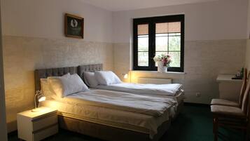 Ein Schlafzimmer mit zwei Betten, einem Nachttisch, einem Sessel, einem Fenster mit Aussicht und einer Heizung.