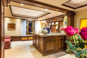 A reception area with a wooden reception desk, a framed picture on the wall, and a window with curtains.