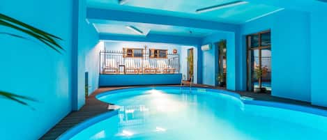 Una piscina interior con vistas despejadas al área de la piscina, tragaluz y zona de estar con barandilla.