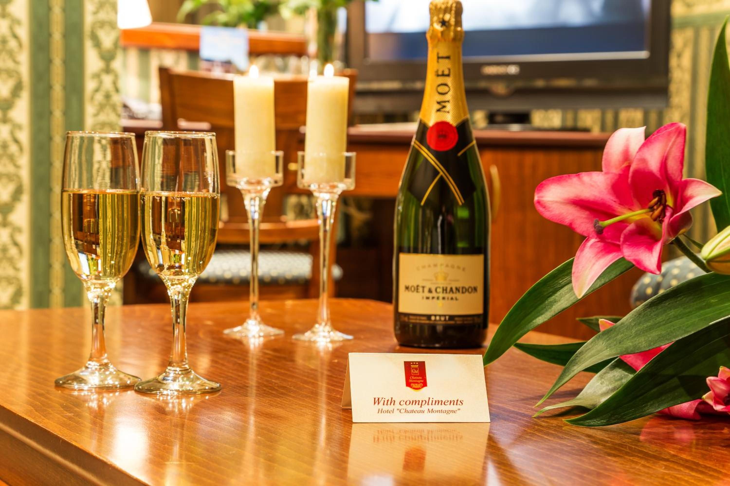 A bar area with a bottle of Moët & Chandon champagne, three glasses of champagne, candles, and a flower arrangement.