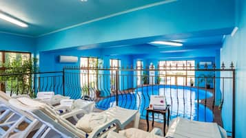 A blue-themed indoor pool area with lounge chairs and a small table.