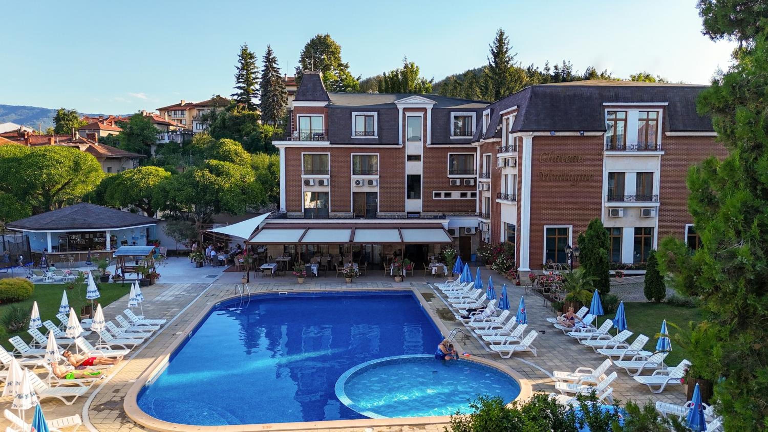 Un hotel con piscina, mobiliario exterior y un patio cubierto.