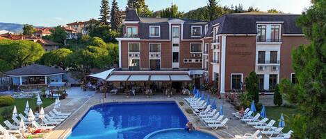 Un hotel con piscina, mobiliario exterior y un patio cubierto.