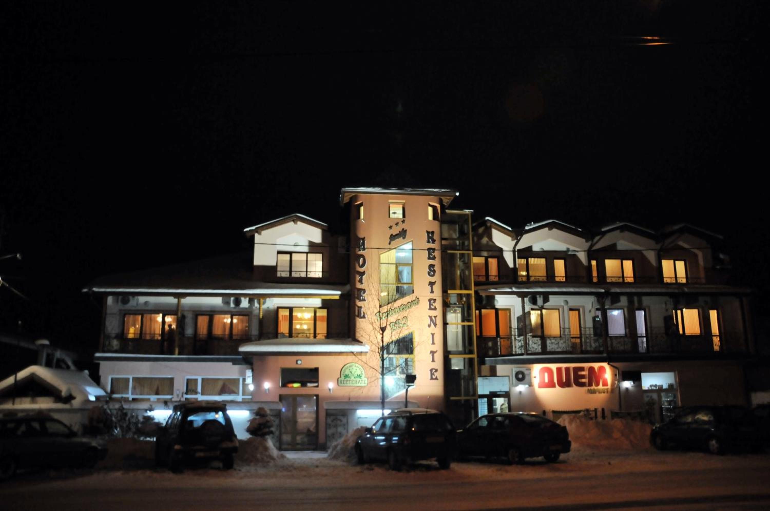 A hotel with multiple floors, a visible restaurant sign, and several parked cars in front.