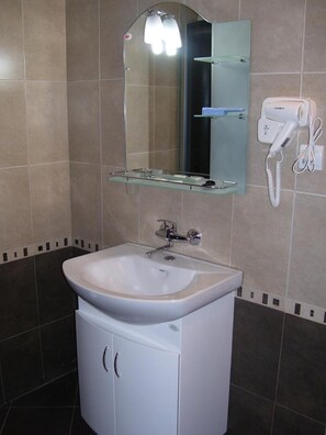 A bathroom with a white sink, a mirror, and a hairdryer on the wall. - Kestenite Family Hotel (Samokov)