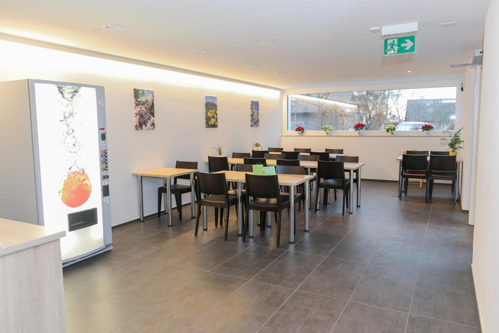 Ein Restaurantinneres mit mehreren Tischen und Stühlen, einem Empfangsbereich und einem Fenster mit Blick.