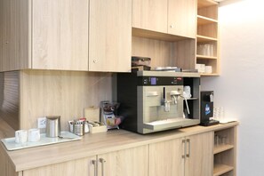 A kitchen with a coffee machine, a tray with cups and utensils, and wooden cabinets. - Hotel Traube Garni (Küttigen)