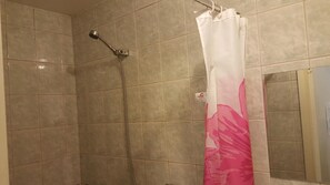 Una ducha con cabezal de ducha de mano y cortina de baño rosa y blanca.