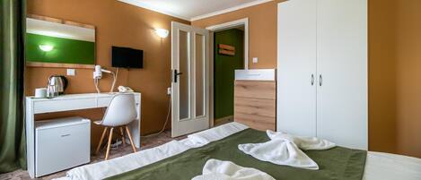 Una habitación de hotel con una cama, un escritorio, una silla, un armario y un televisor.