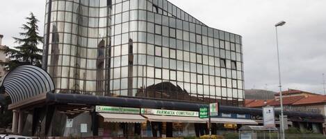 A modern building with a curved glass facade, a pharmacy, and a medical clinic on the ground floor.