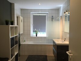 Un baño moderno con ventana, bañera y tocador.