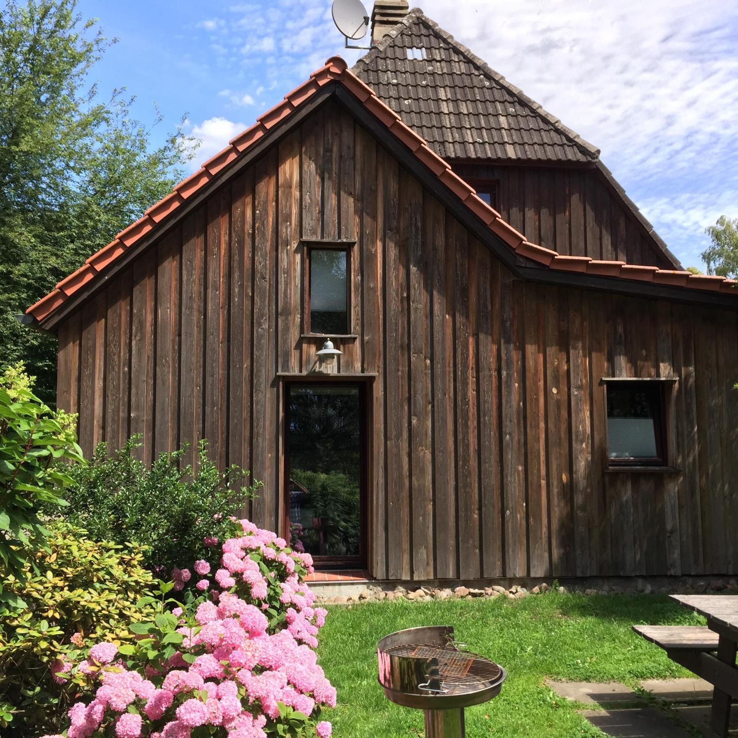 A wooden barn with a sloped roof, a satellite dish, and a small porch area.