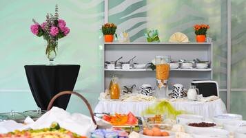 A buffet setup with various food items and a decorative wall with a wave pattern.