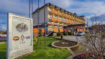 A hotel with a modern design, featuring a central courtyard and a signboard with historical information.