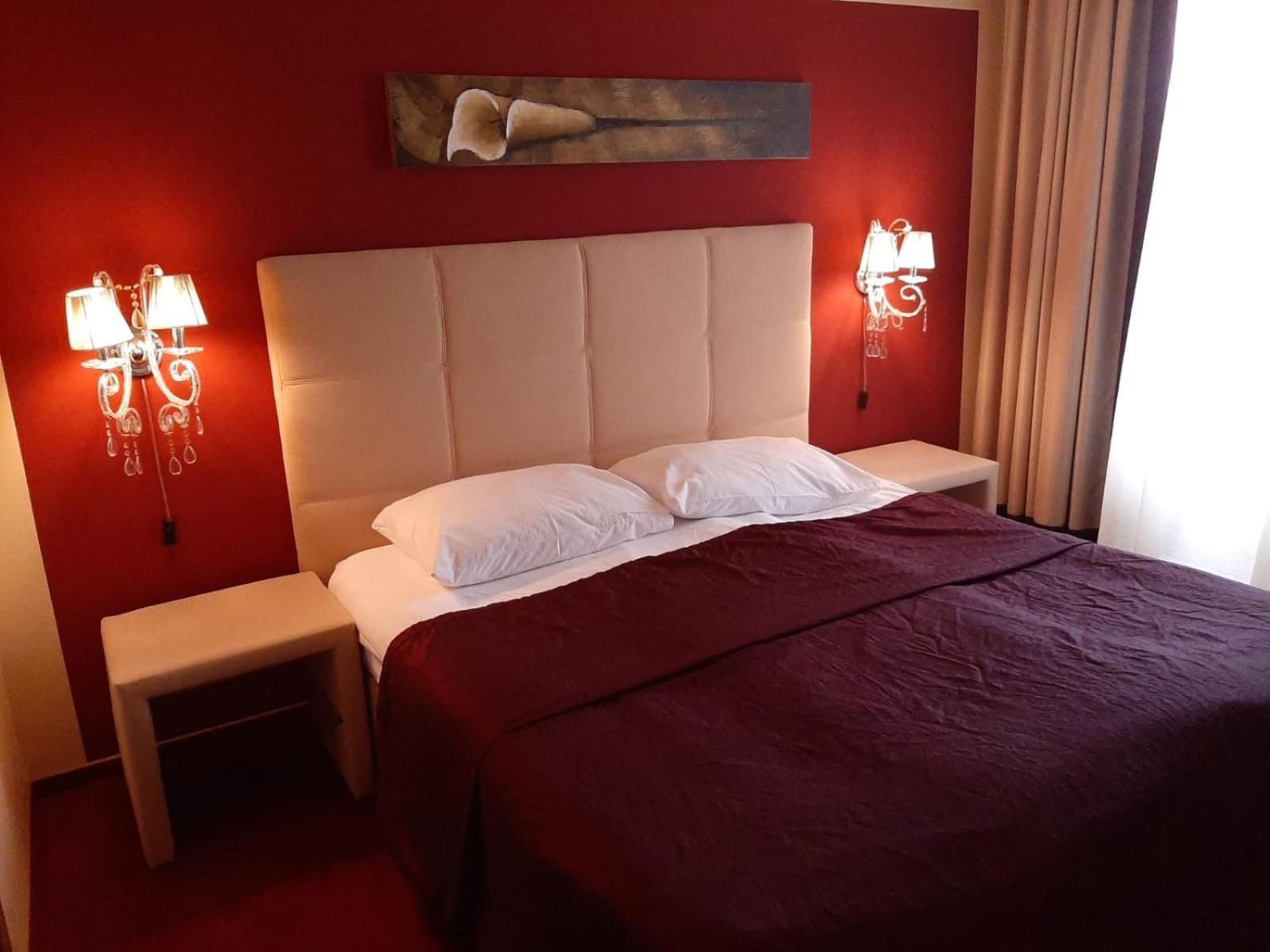 A hotel room with a large bed, two bedside tables, and wall-mounted lamps.