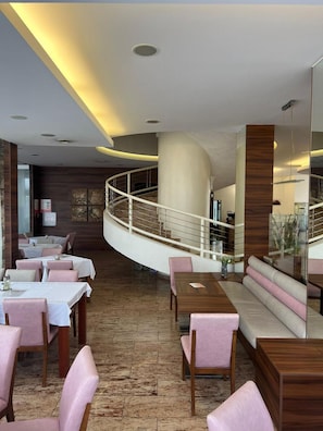 A modern restaurant with a curved seating area, a wooden floor, and a glass railing overlooking a lower level.