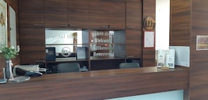 A reception desk with a wooden finish, a clock, and a welcome sign.
