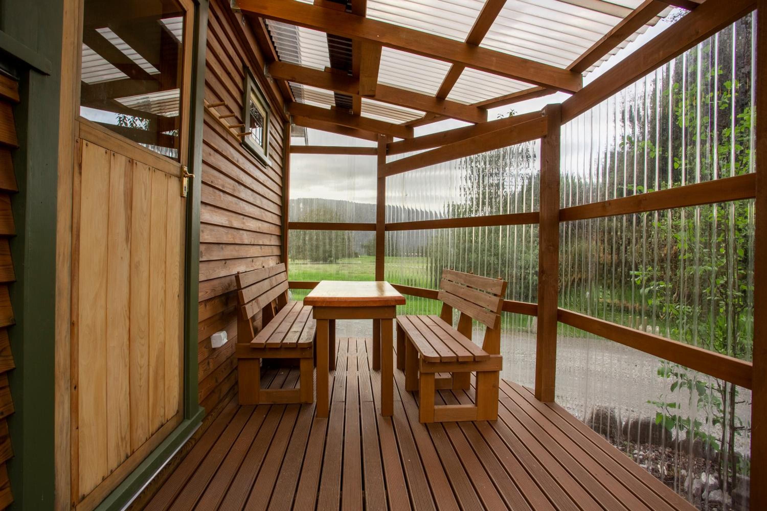 A wooden deck with a table and two benches, overlooking a forested area.