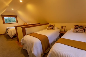 Quarto com duas camas, uma janela e cabeceira de madeira.