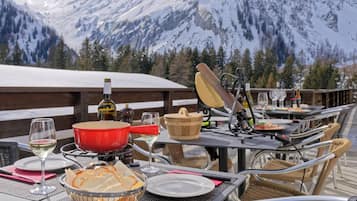 An outdoor dining area with tables, chairs, and a mountain view.
