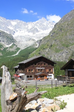 A mountain lodge with a wooden facade, a restaurant sign, and a view of snow-capped mountains.