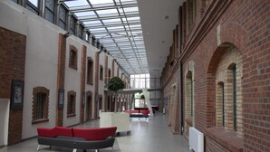 Ein großzügiger Innenraum mit hohen Decken, freiliegenden Backsteinwänden und einem zentralen Atrium mit Sitzgelegenheiten.