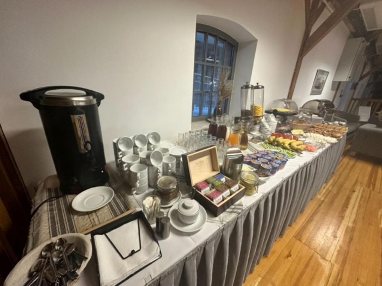 A buffet table with various food items, a coffee maker, and dining ware.