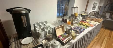 A buffet table with various food items, a coffee maker, and dining ware.