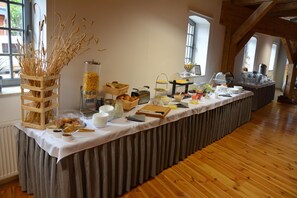 A buffet setup with various food items and a decorative vase of wheat stalks. - Hostel Mi Odzynarodowe Centrum Spotka N M Codzie Y (Torun)