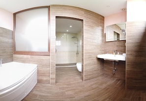 A modern bathroom with a curved design, a bathtub, a shower area, and a vanity with a mirror. - Clepsydra Residence (Plovdiv)
